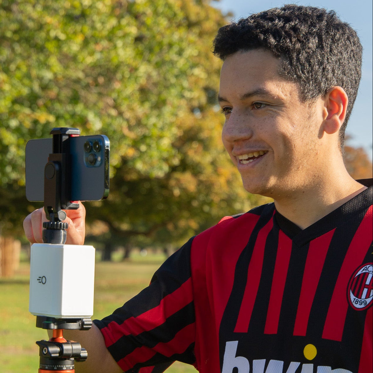 Jeremy using a Pitchwise Mount on a tripod in an outdoor setting with trees and grass.